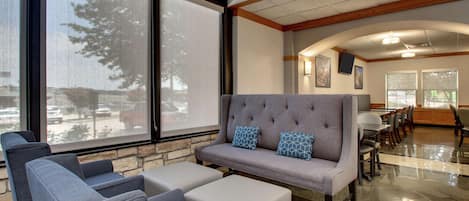 A modern lobby with a grey sofa, blue armchairs, and a stone accent wall.
