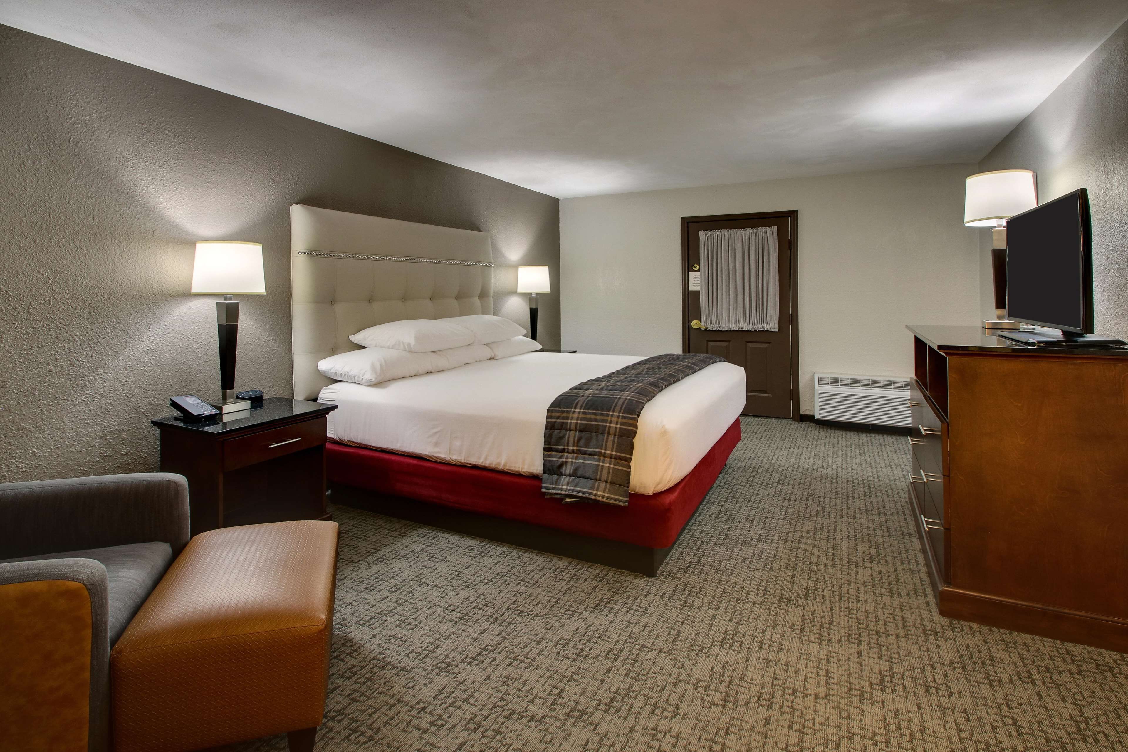 A hotel room with a large bed, a desk with a computer, a chair, and a television.