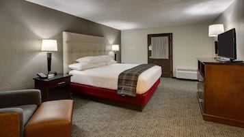 A hotel room with a large bed, a desk with a computer, a chair, and a television.