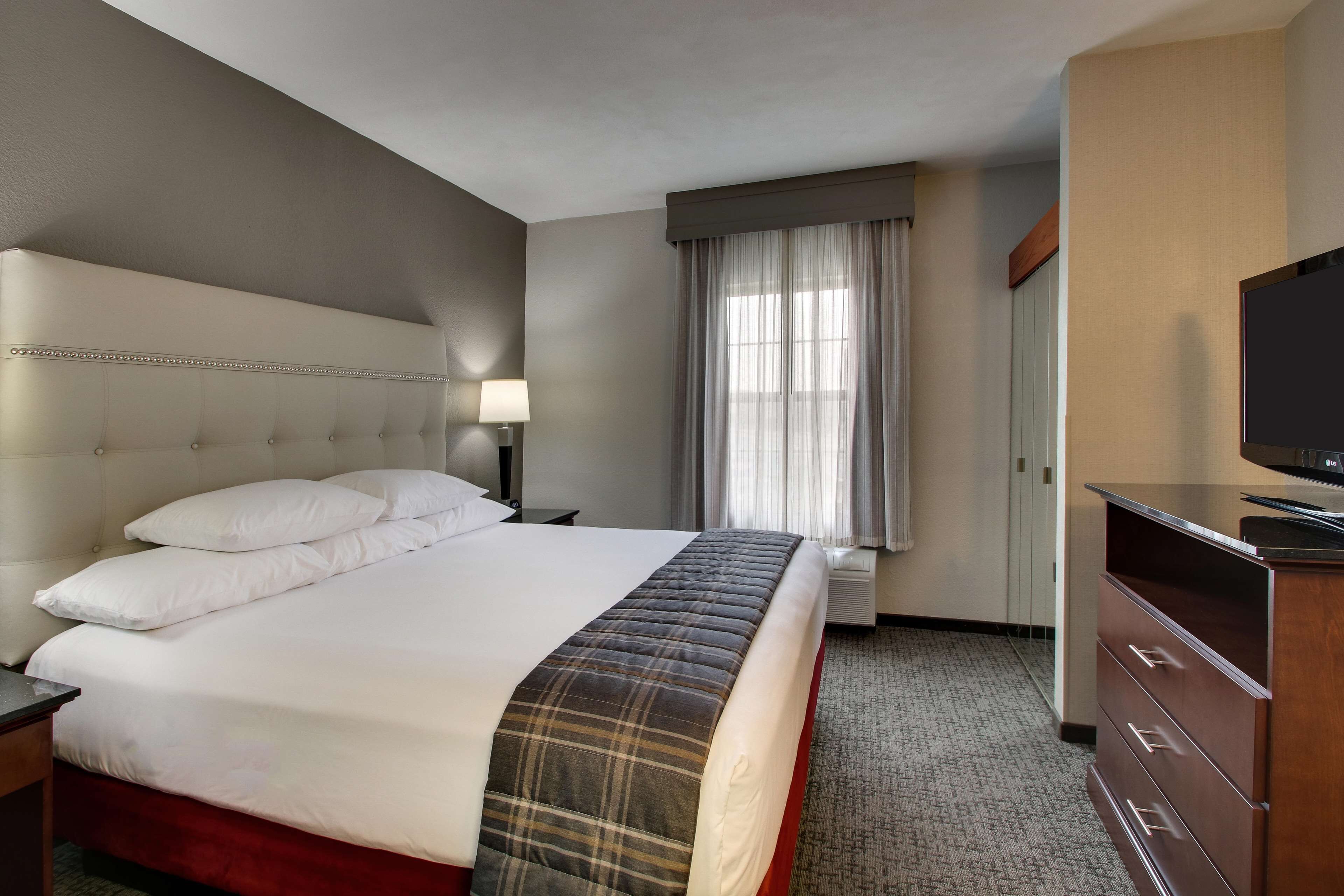 A hotel room with a large bed, a television, a desk, and a wardrobe.