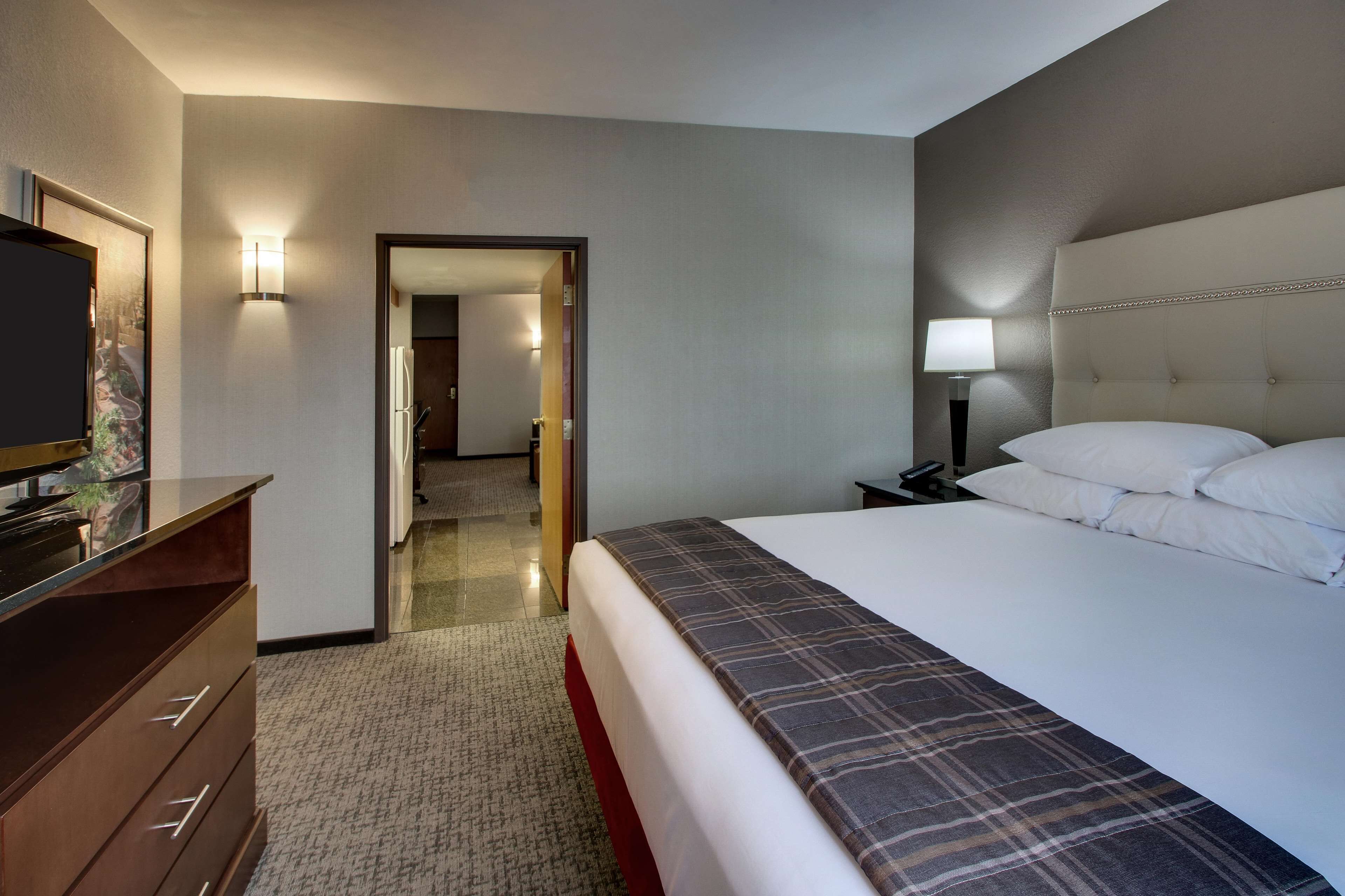 Una camera d'albergo con un letto, una televisione, un comodino e una lampada.