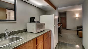 A modern kitchen with granite countertops, a stainless steel sink, a white refrigerator, and wooden cabinets.