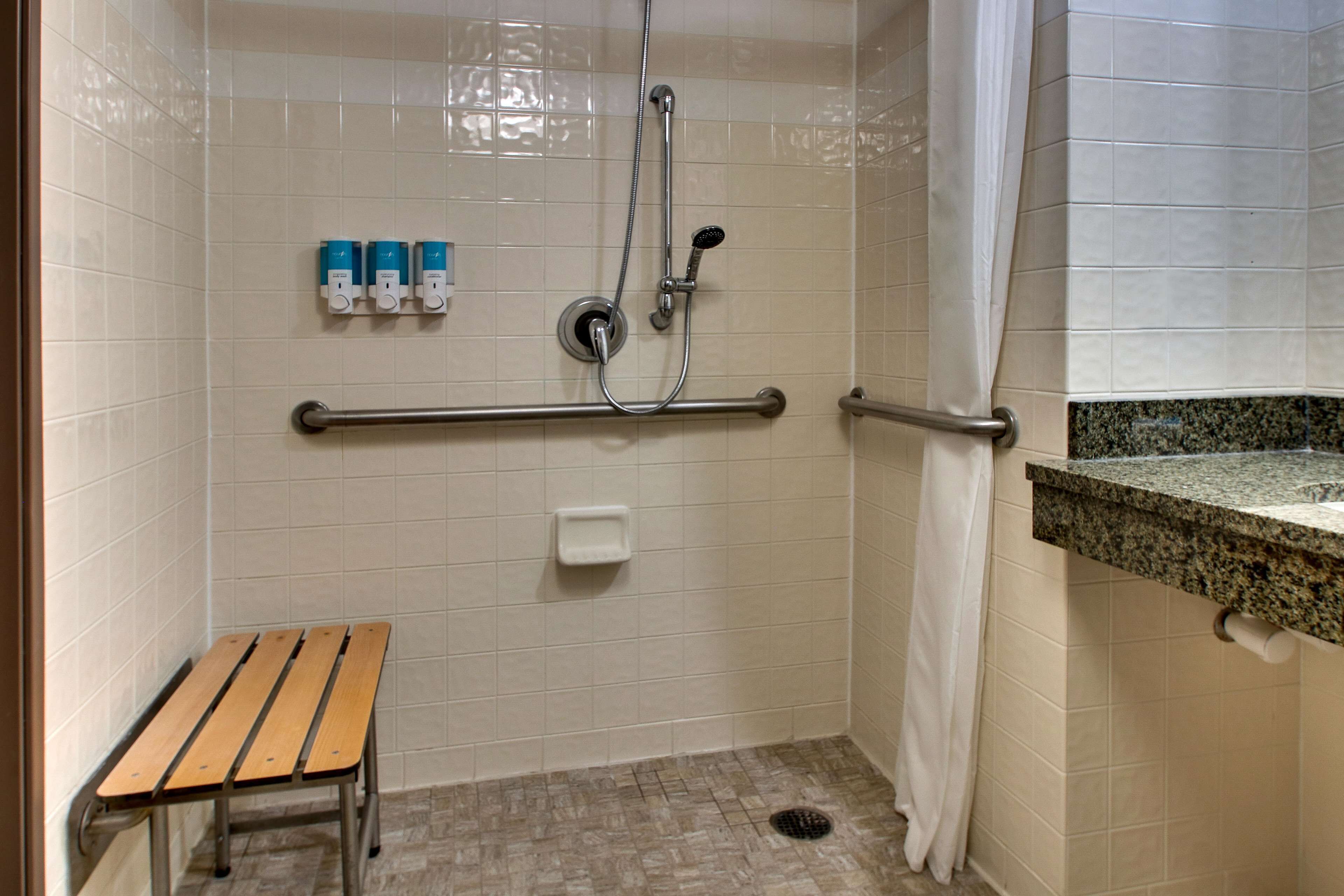 Un espace douche équipé d’un banc, de barres d’appui et d’un porte-serviettes.