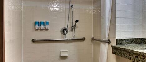 Un espace douche équipé d’un banc, de barres d’appui et d’un porte-serviettes.