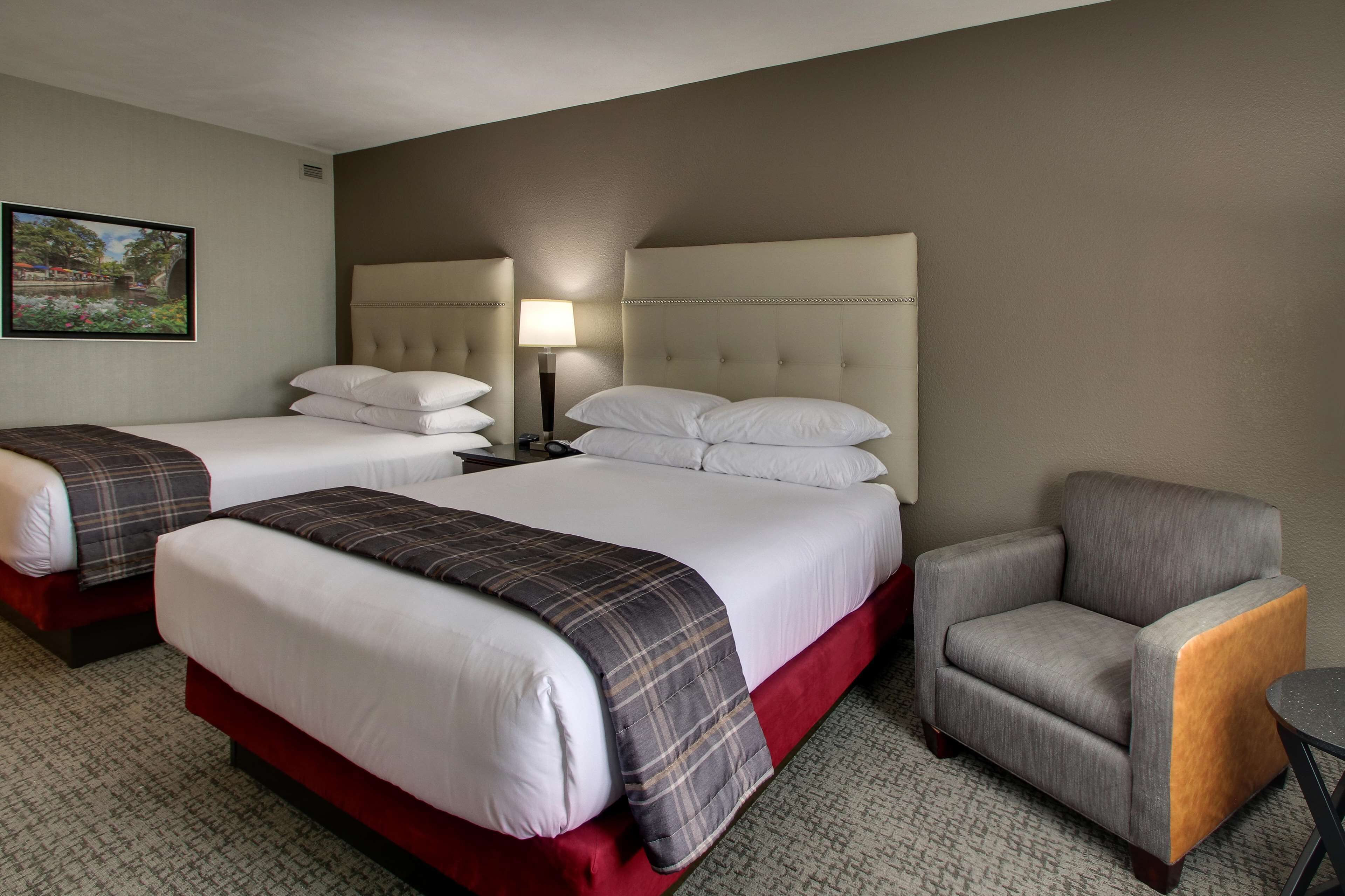 Une chambre d’hôtel avec deux lits, une chaise et une lampe.