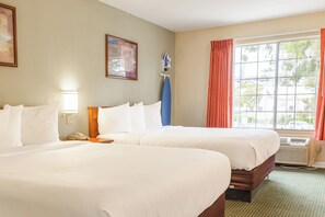 Two large beds with white linens, a bedside table, lamp, and telephone.