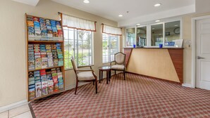 A reception area with a check-in counter, a bookshelf with travel brochures, two chairs, and a patterned carpet. - Hotel Avenida, San Clemente Beach (San Clemente)