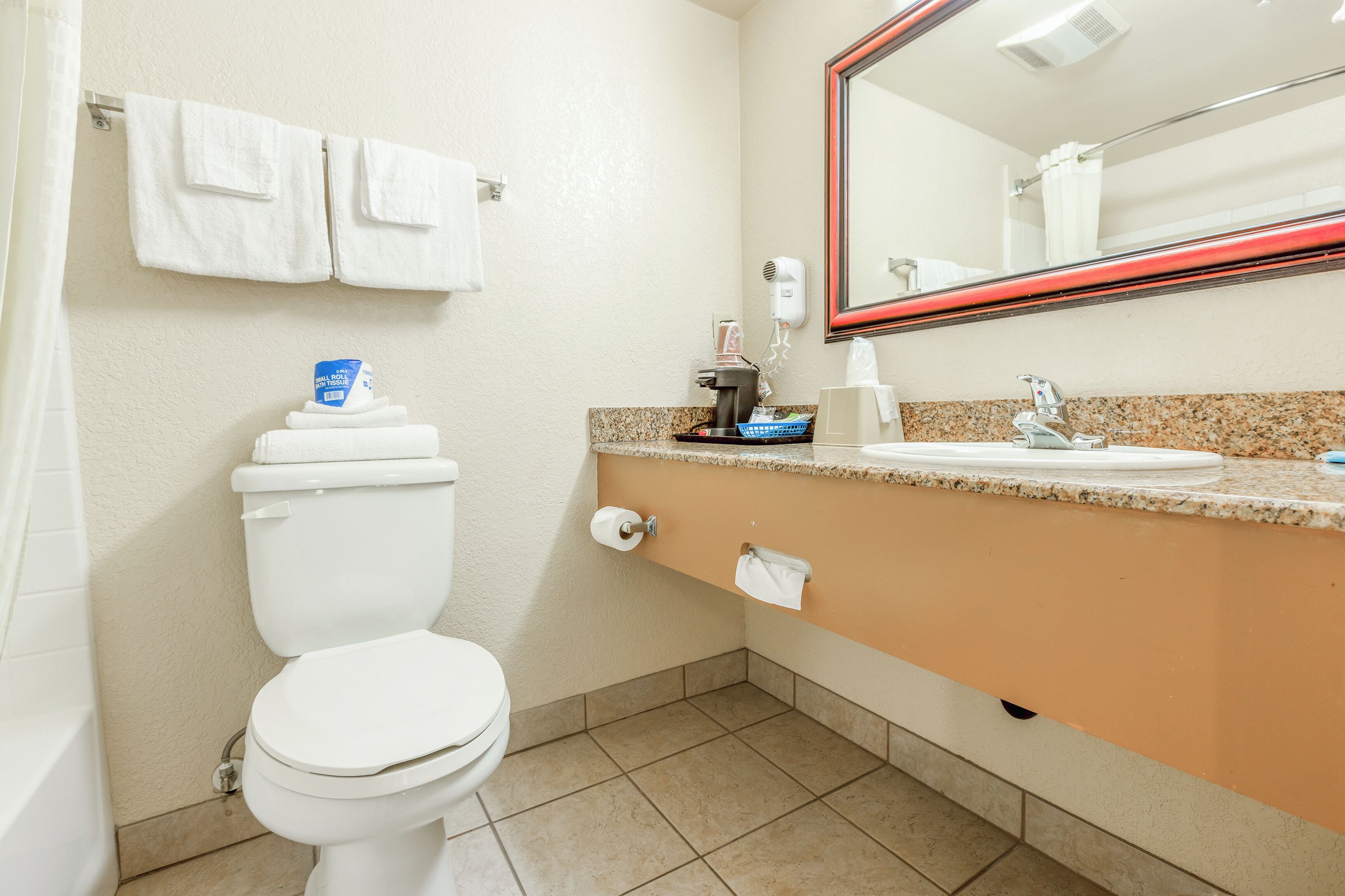 A bathroom with a toilet, sink, and mirror.