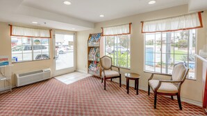 A waiting area with a patterned carpet, two chairs, a small table, a radiator, and a window with a view of the outside. - Hotel Avenida, San Clemente Beach (San Clemente)