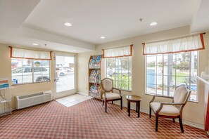 Guests can check in at the reception desk, surrounded by a patterned floor and comfortable seating.