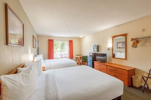 A hotel room with two beds, a desk, a television, and a mirror.