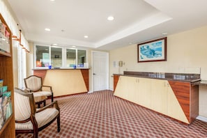 A reception area with a counter, chairs, a door, and a framed picture on the wall.