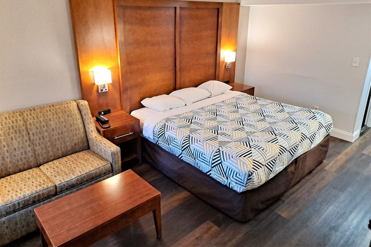 Ein Hotelzimmer mit einem Bett, einer Couch, einem Nachttisch und einem Beistelltisch.