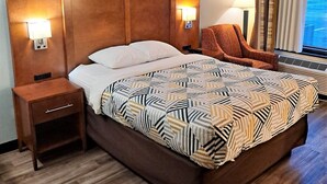 A hotel room with a large bed, a nightstand, two wall-mounted lamps, and a window with curtains. - Motel 6 Catonsville, MD – Baltimore West (Catonsville)