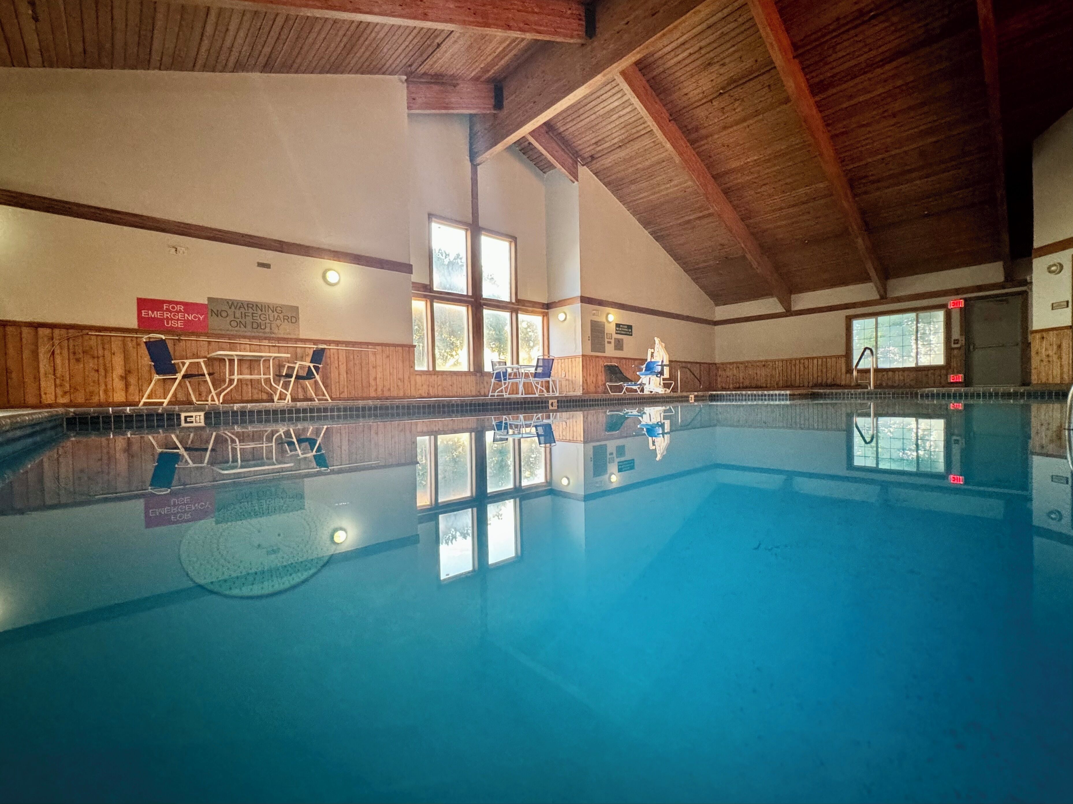 Una piscina interior con paredes de madera, techo transparente y ventanas.
