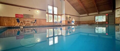Indendørs swimmingpool med trævægge, klart loft og vinduer.