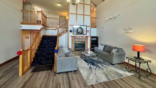 A spacious living room with a fireplace, a staircase, and a chandelier. - Quality Inn & Suites Alexandria (Alexandria)