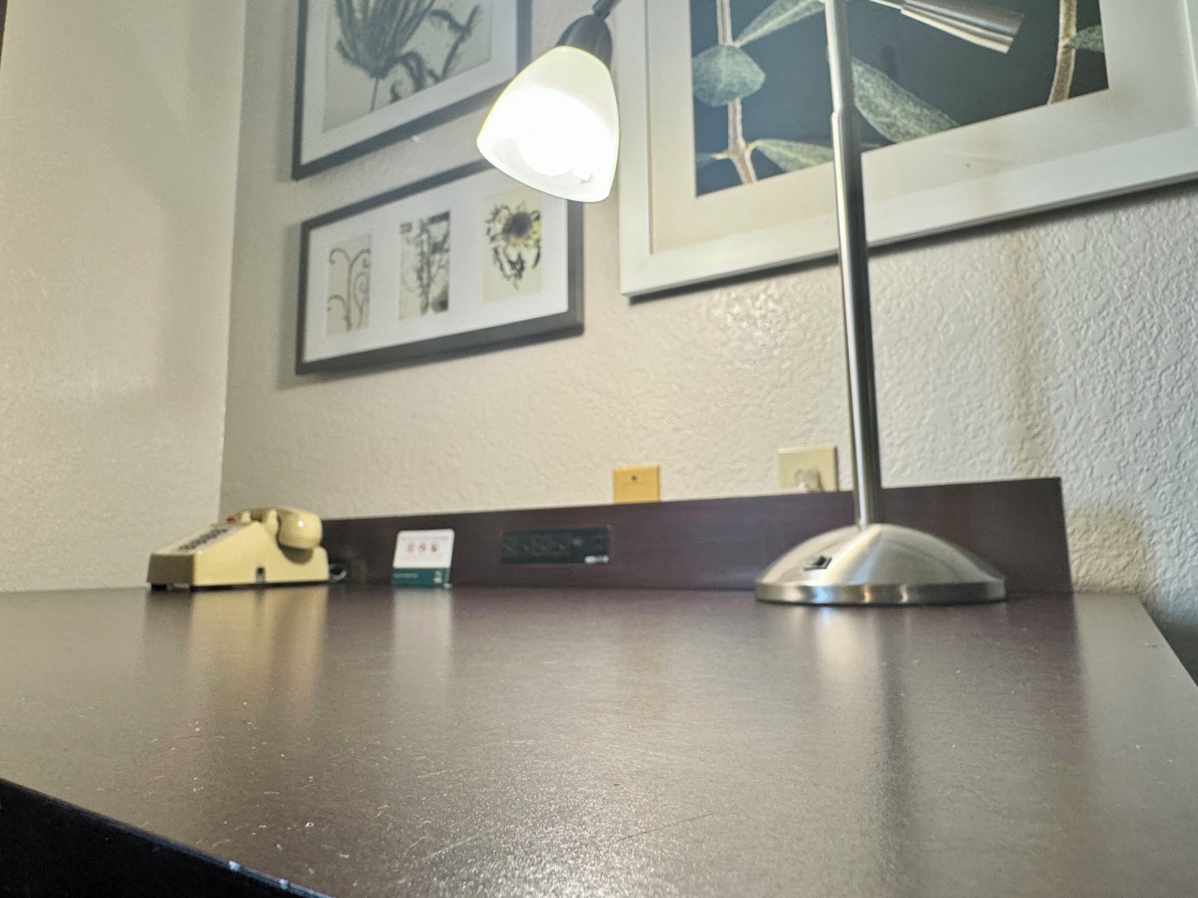 Un escritorio con una lámpara, un teléfono y un pequeño portaletras.