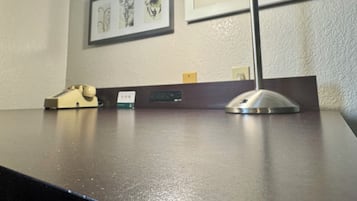 Un escritorio con una lámpara, un teléfono y un pequeño portaletras.