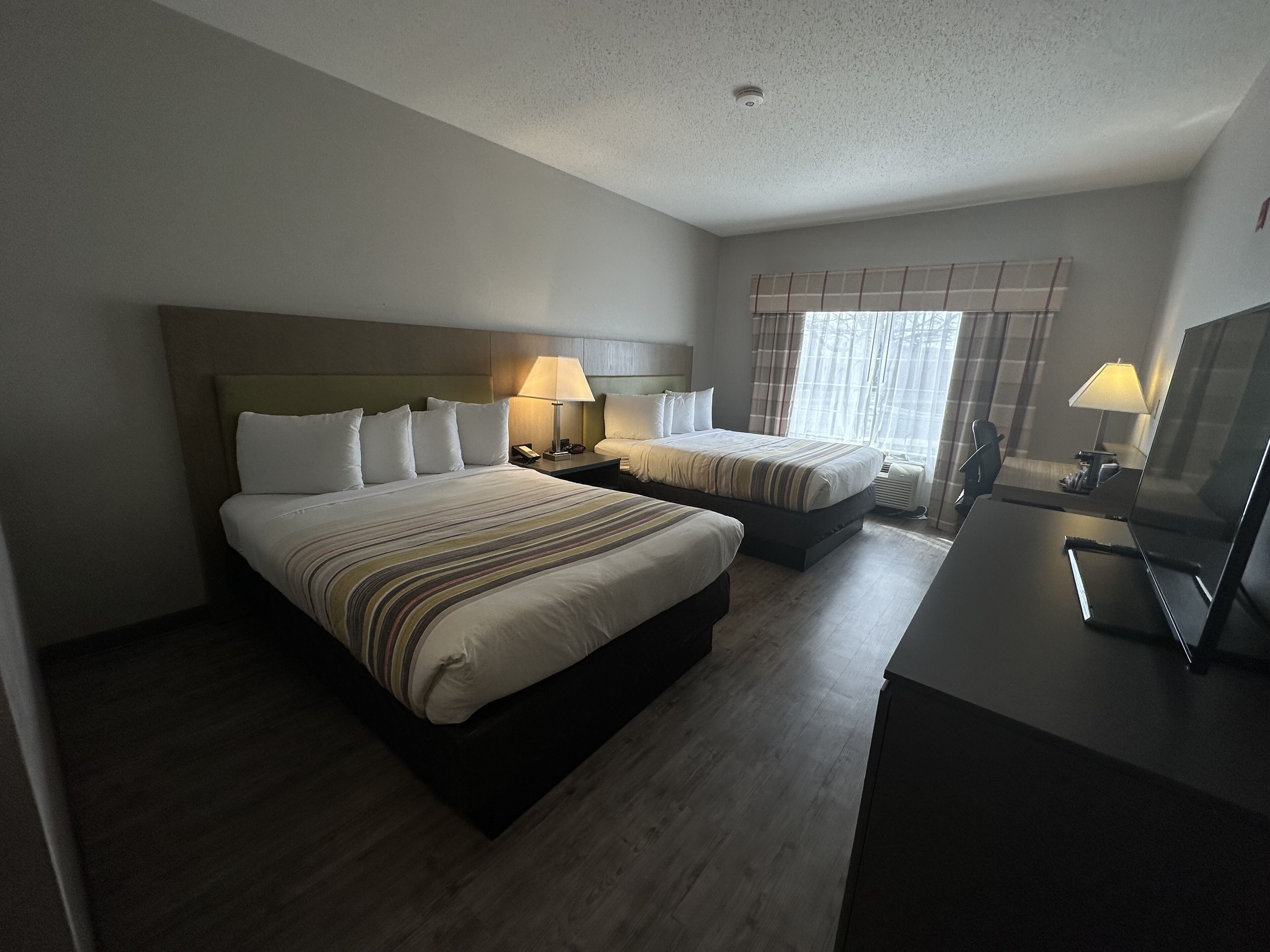 A hotel room with two beds, a desk, and a television.