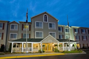 A multi-story hotel with a central entrance, a covered front porch, and a flagpole.