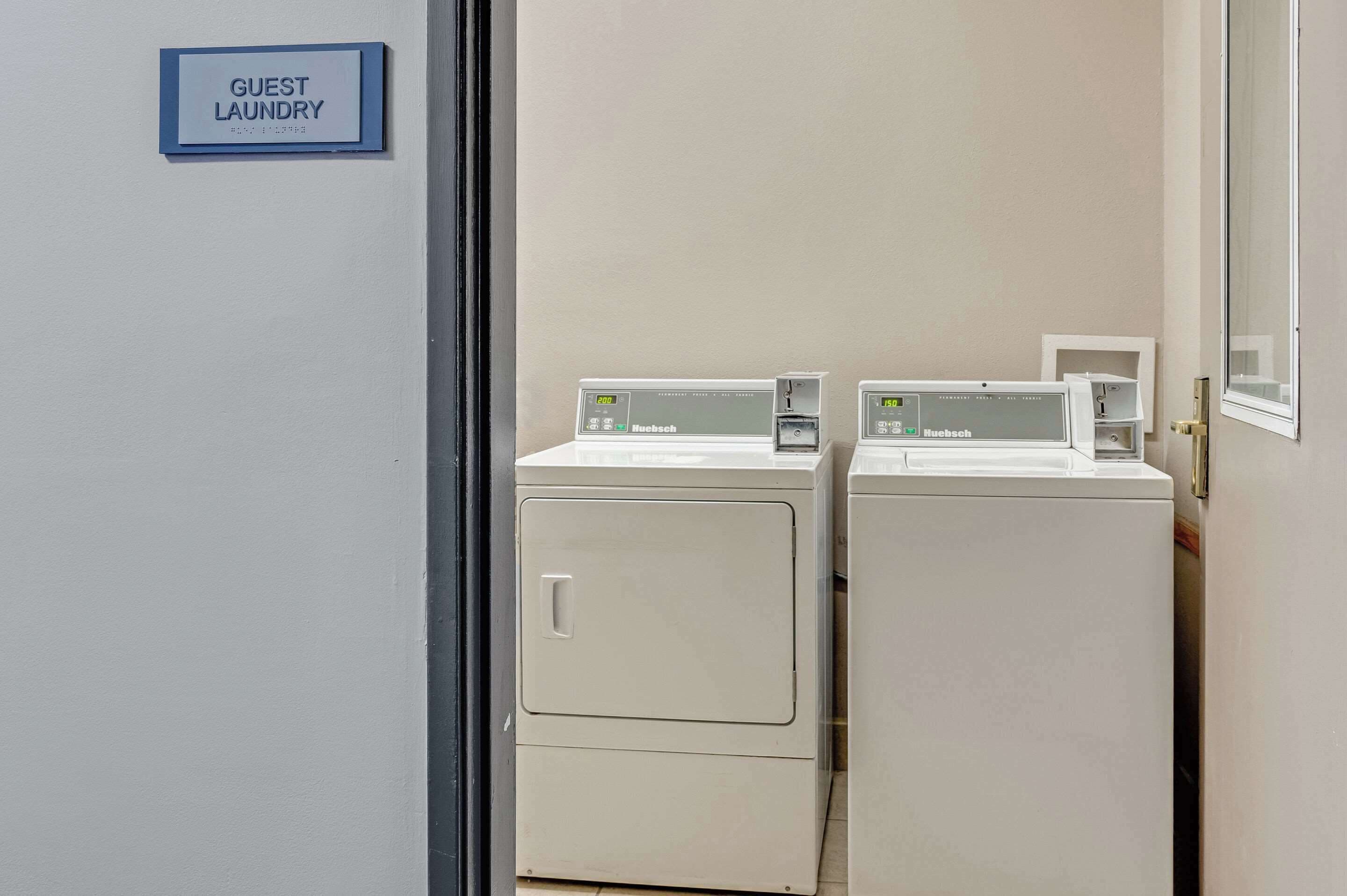 A guest laundry area with two Haebsch brand washing machines and a sign indicating it is for guests.