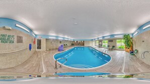 Une piscine intérieure, avec une trousse de premiers secours à la réception, un panneau indiquant la présence d’un sauveteur et un banc près de la piscine.