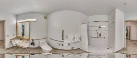 A modern bathroom with a curved vanity, a toilet, a shower with a glass door, and a large mirror.