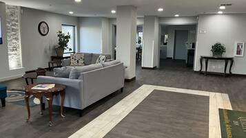 Een moderne woonkamer met een grijze bank, een houten salontafel en een tapijt met een patroon.