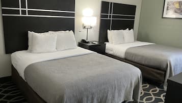 Une chambre d’hôtel avec deux lits, une table de chevet avec une lampe et une moquette à motifs.