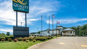 A Quality Inn sign, a parking lot, and a building with American flags. - Quality Inn Jacksonville near Little Rock Air Force Base (Jacksonville)