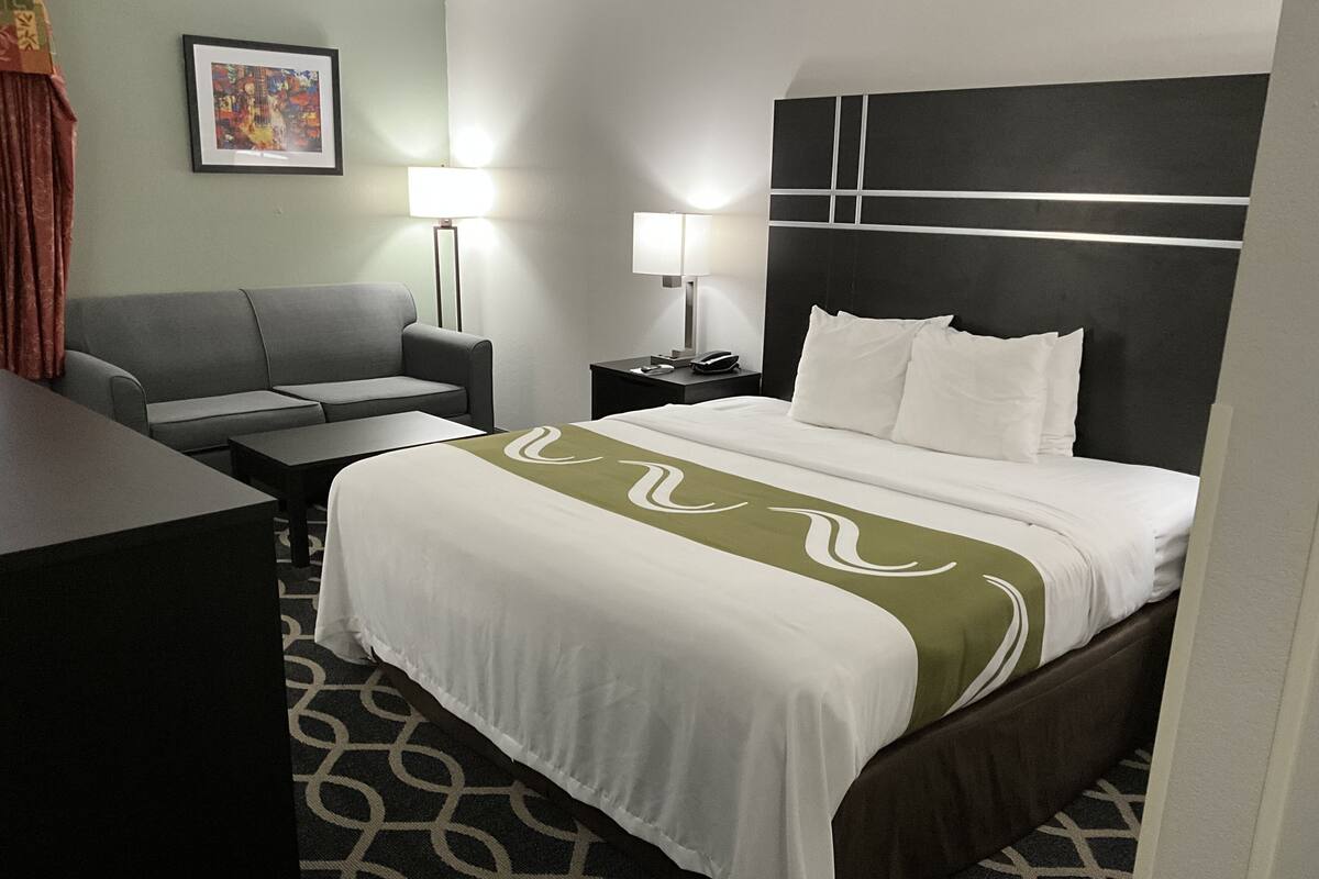 Ein Hotelzimmer mit Bett, Sofa, Schreibtisch und Nachttisch.
