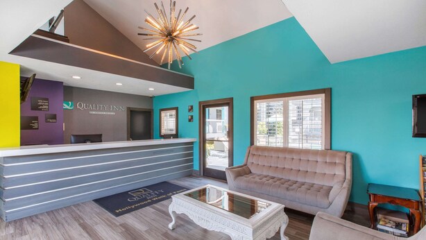 A reception area with a modern design, featuring a reception desk, a seating area with a sofa, a coffee table, and a chandelier. - Quality Inn Near Hollywood Walk of Fame (Los Angeles)