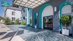A hotel entrance with a sign reading "Quality Inn," a covered walkway, and a parking lot. - Quality Inn Near Hollywood Walk of Fame (Los Angeles)