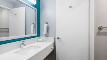 A modern bathroom with a white sink, a large mirror, and a door.