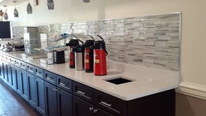 A modern kitchen with a white countertop, dark cabinets, and a glass backsplash. - Best Western Plus Madison (Madison)