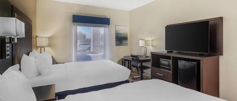 Una habitación de hotel con dos camas, un escritorio, un televisor y un minibar.