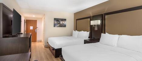 A hotel room with two beds, a desk, a TV, and a painting on the wall.