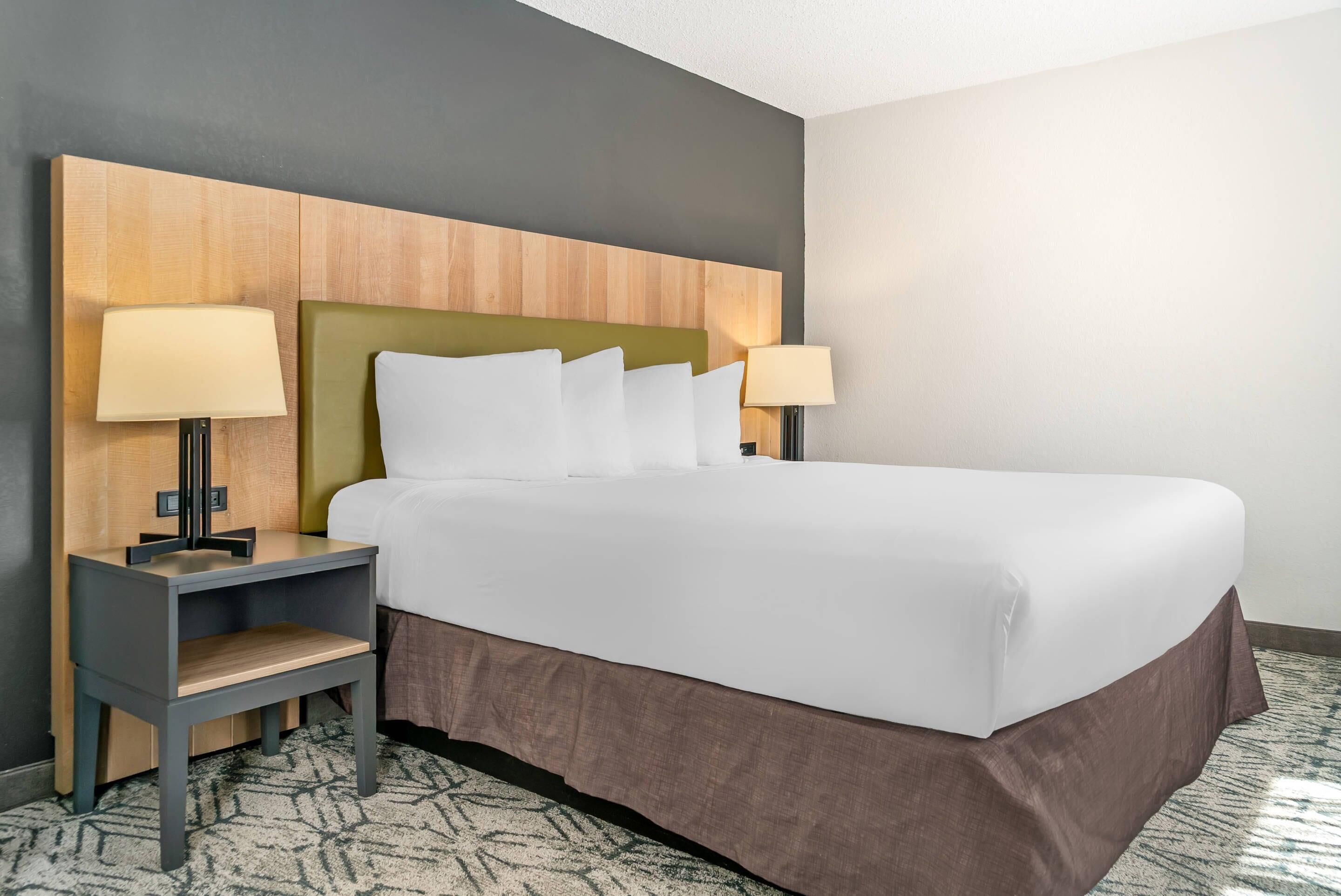 A hotel room with a bed, two bedside tables, a nightstand, and a headboard.