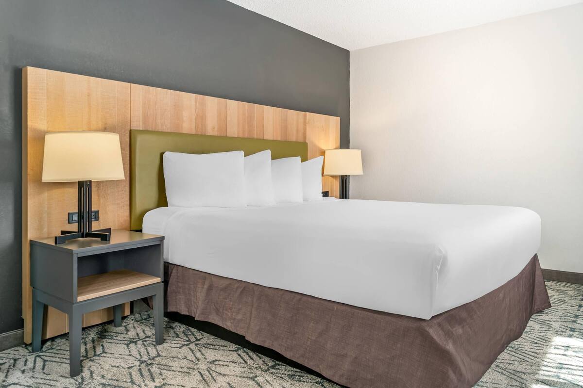 A hotel room with a bed, two bedside tables, a nightstand, and a headboard.