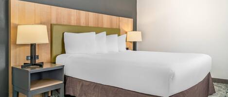 A hotel room with a bed, two bedside tables, a nightstand, and a headboard.