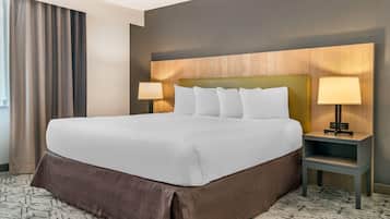 Habitación de hotel con una cama grande, dos lámparas de noche, una mesita de noche y una alfombra estampada.