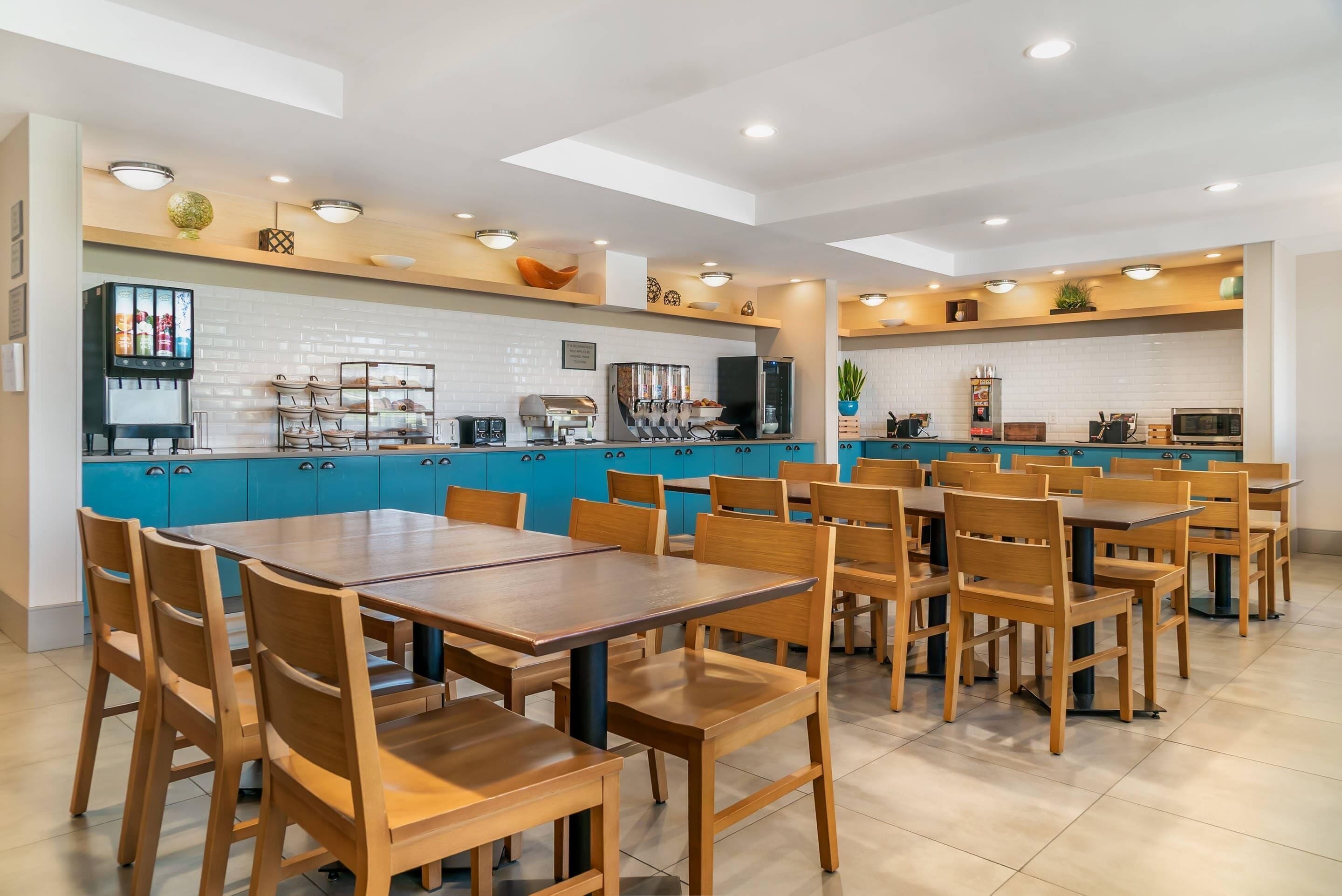 Un restaurante moderno con un área central de comedor, cocina y armarios azules.