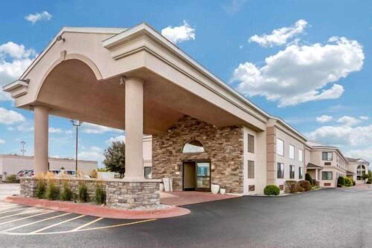 A hotel with a stone facade, a covered entrance, and a parking lot.