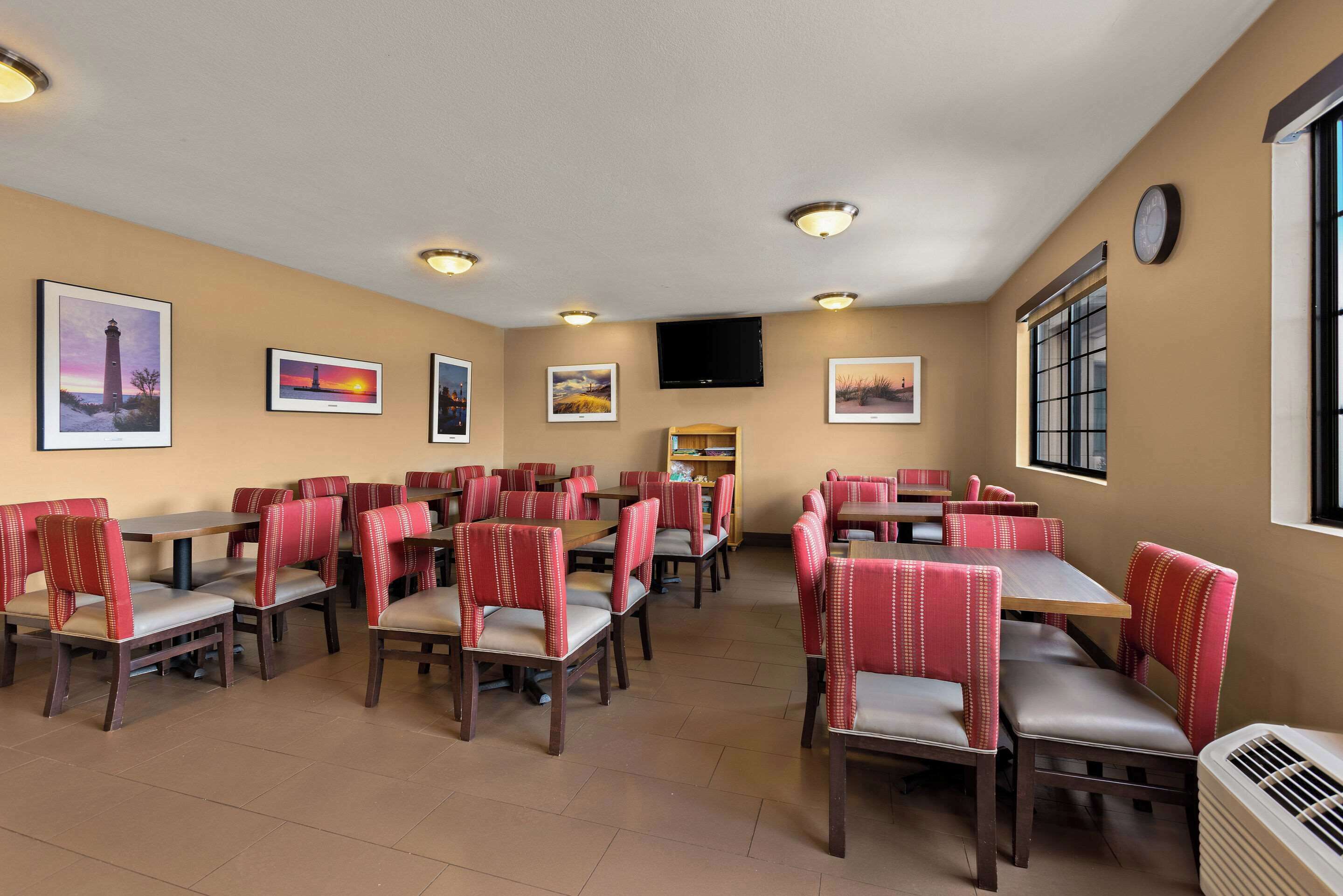 A dining area with booths and tables, beige walls, and artwork.