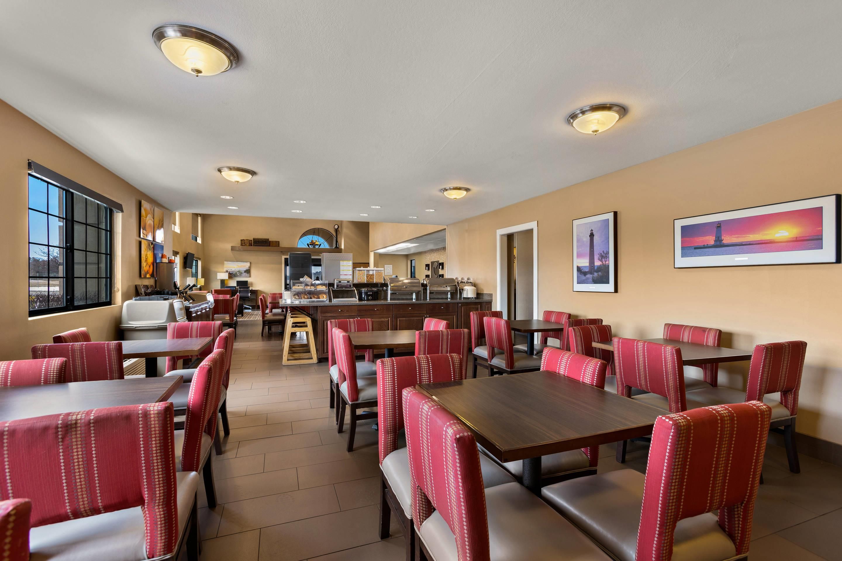 A restaurant with booths and tables, a kitchen area, and a large window.