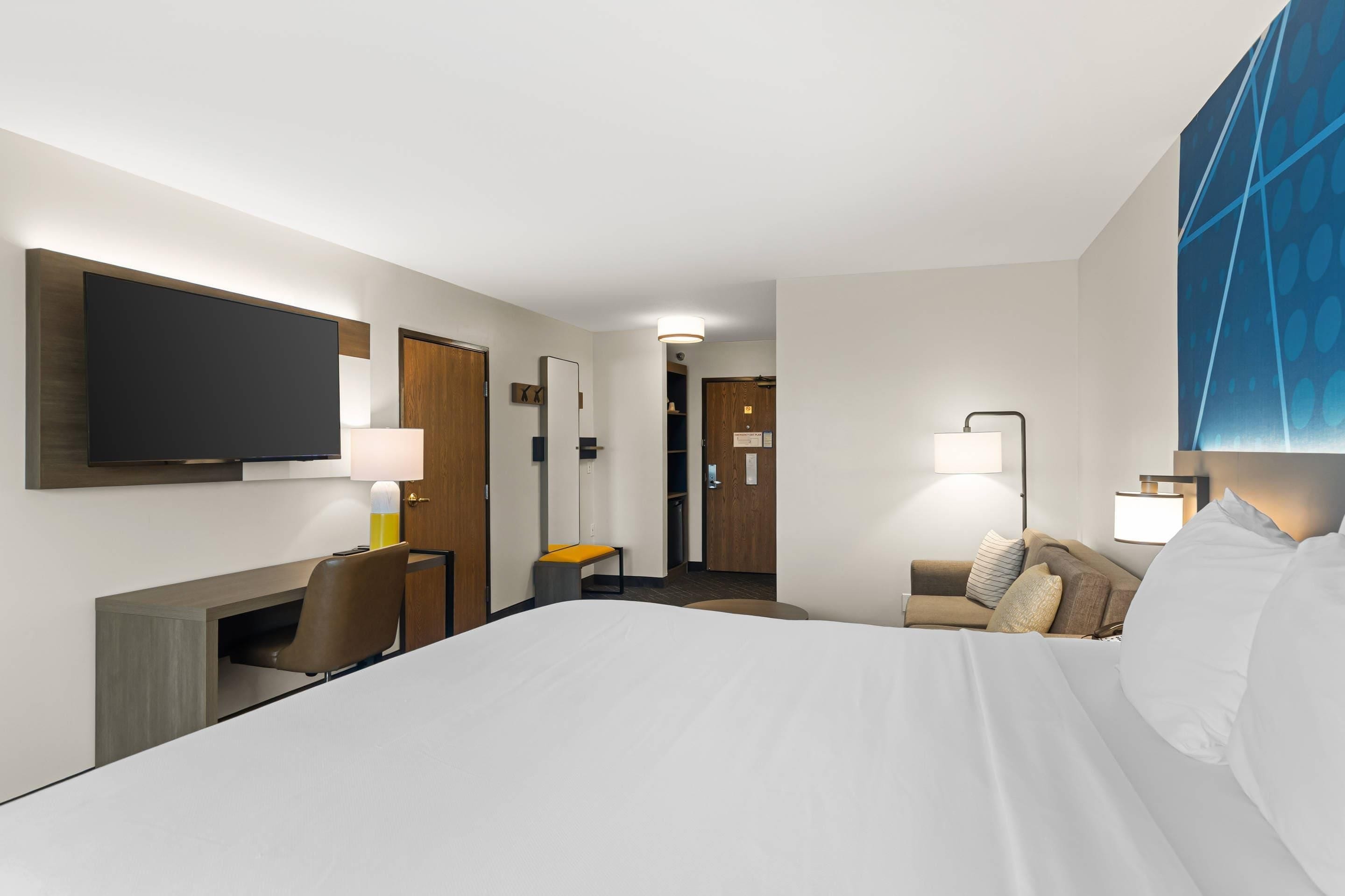 Een hotelkamer met een bed, een bureau, een stoel, een televisie en een bank.