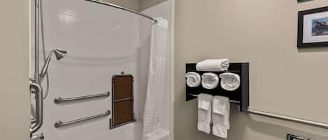 A modern bathroom with a walk-in shower, grab bars, a towel rack, and a toilet paper holder.