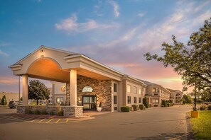 A hotel with a covered entrance, a parking lot, and a landscaped area with trees. - Comfort Inn & Suites Ludington near US-10 (Ludington)