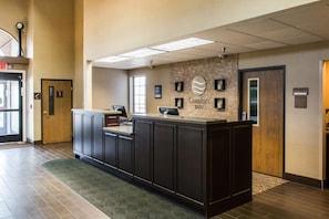 A reception area with a dark wooden reception desk, a clock, and a sign that reads "Comfort Inn." - Comfort Inn & Suites Ludington near US-10 (Ludington)